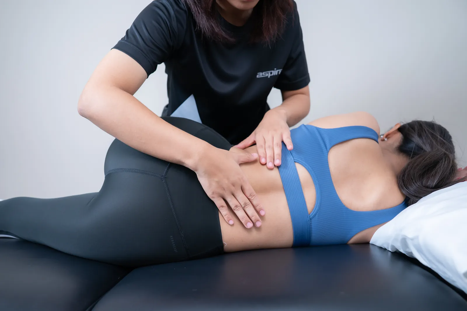 นักกายภาพบำบัดรักษาหลังส่วนล่างของคนไข้ที่นอนตะแคง ที่ Aspire Physio Bangkok